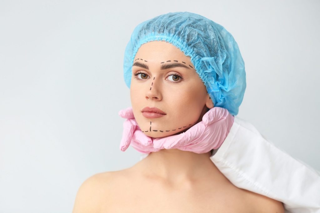chirurgie esthétique touchant le menton du visage d'une jeune femme portant une charlotte sur ses cheveux, sur fond blanc