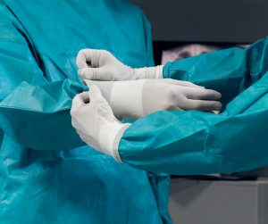 Des mains de médecins portant des blouses chirurgicales bleues et des gants en latex blancs